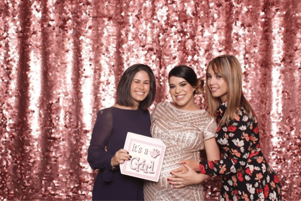 Friends in front of photo booth holding props