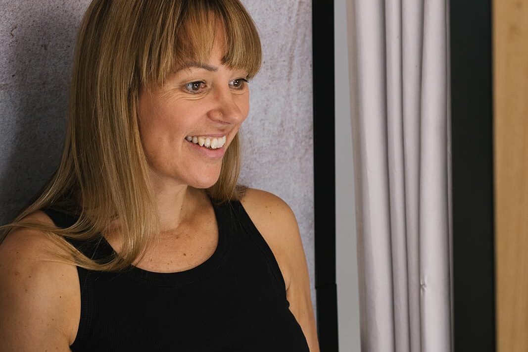 Woman with short blonde hair posing for a photo with an enclosed booth