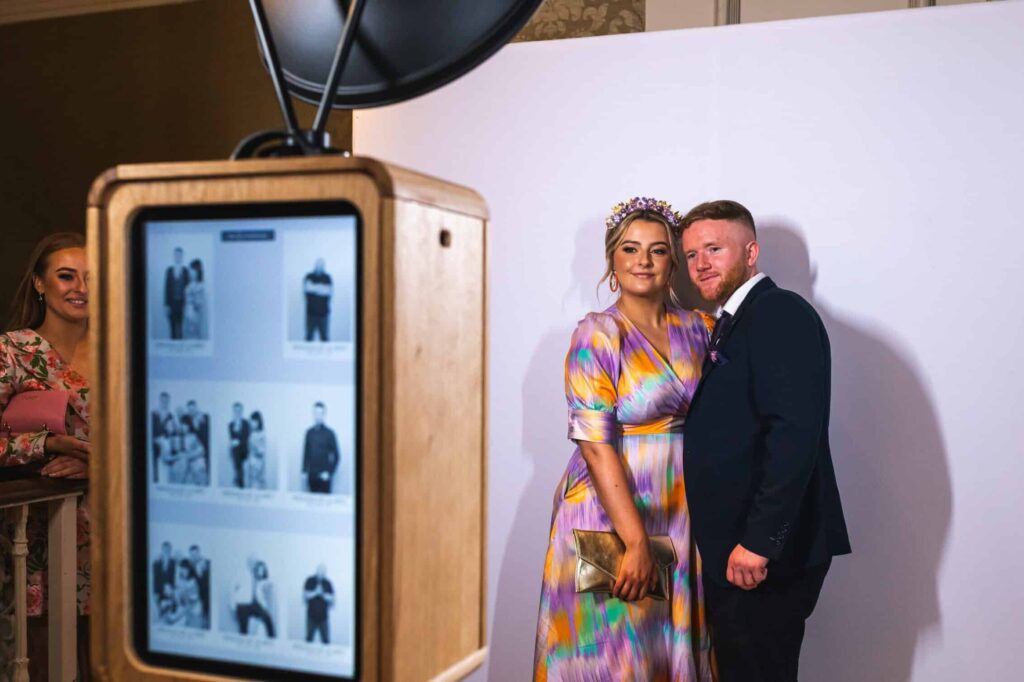 A lovely couple of guests at a wedding or party, posing in front of a backdrop to get photos taken by the Everybooth