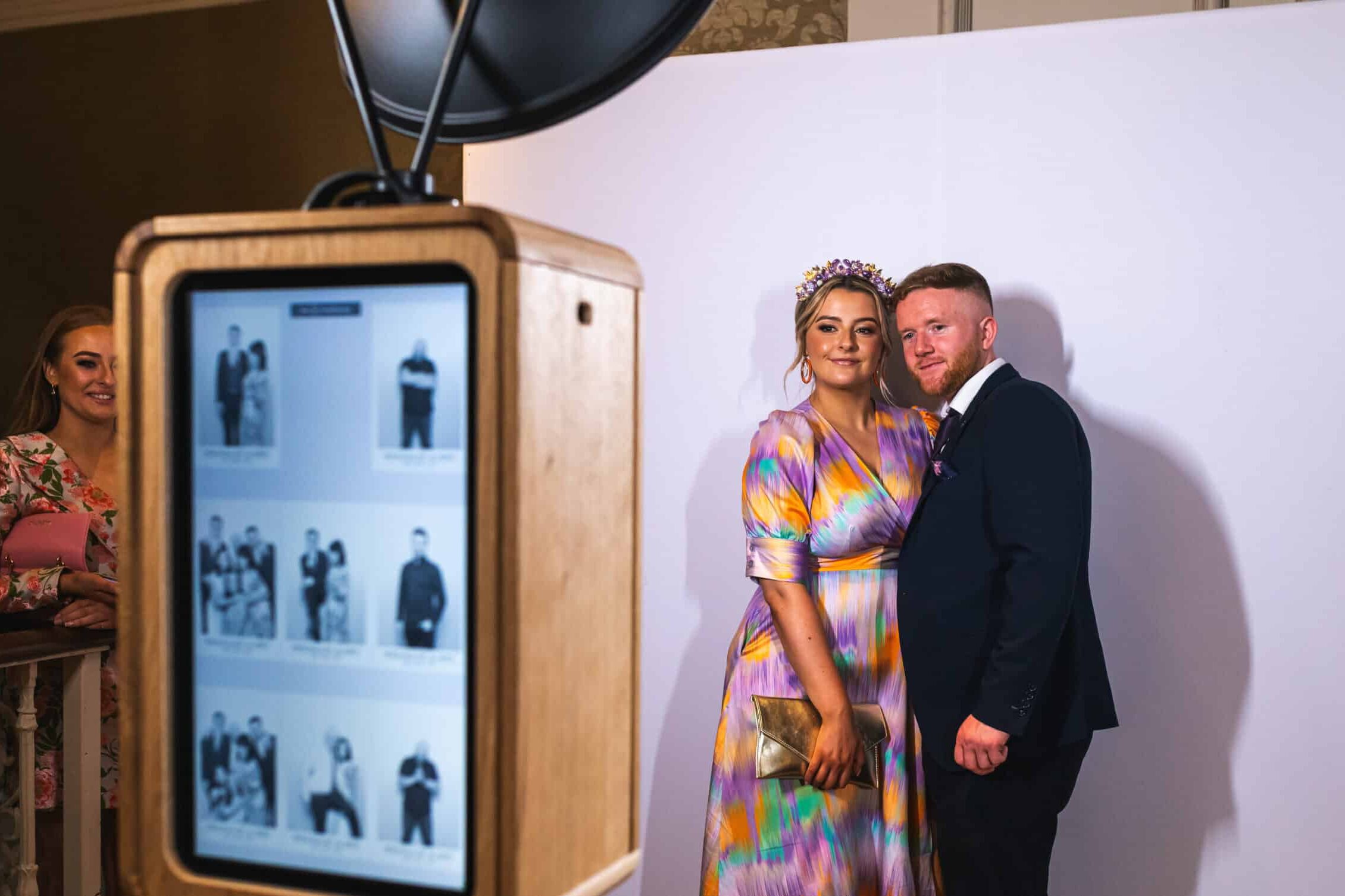 A lovely couple of guests at a wedding or party, posing in front of a backdrop to get photos taken by the Everybooth