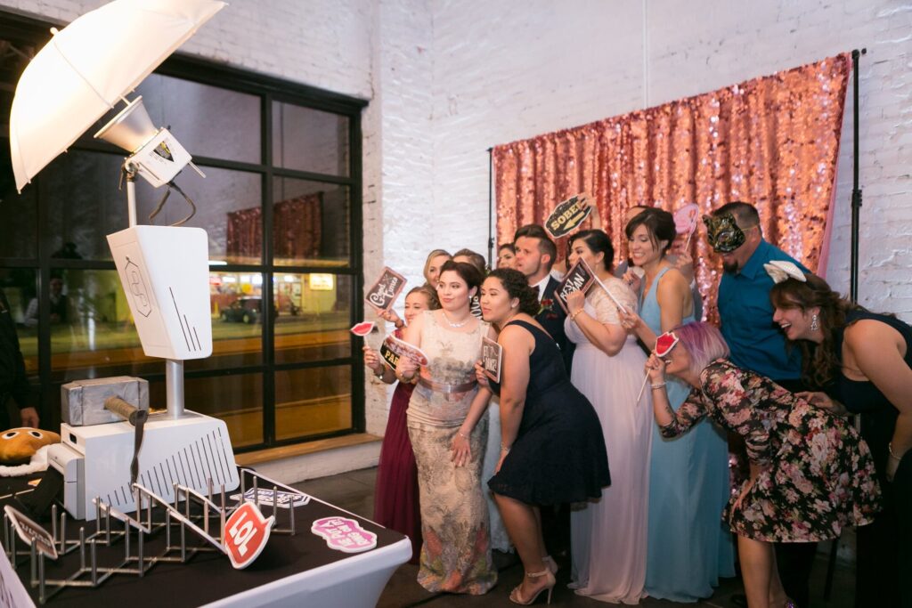 Large group of people taking a photo with an open air photo booth in front of a pink background
